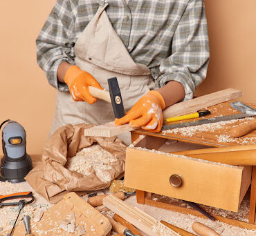 Cropped shot of unrecognizable skilled female jointer uses carpentry tools holds hammer involved in woodwork works in workshop dressed in checkered shirt overalls and gloves enjoys her profession SSUCv3H4sIAAAAAAAACpyRwW7DIAyG75P2DhHnRkpCk7R7lWoHB2iDSqEC0mmq+u4zkFQ+75b/s/3zO35+flQVmyBowb6qZ1KotTFLiB6idhZxs1u5V1YqT8nD86GhADRVSurovAZD4QRRzBZuCqFdjEn4lYssRIhLUCFlWZGAqC7oUeDbogQ+FV1thVzECSwxtiMsLFNmGyrm/5osH9/vhS/Kit8cmCzilVFQFjmVVnb9icrf6GqwSO3IVg8nwKQGTpzuXgttL2TMxTkfYRsTbrHRpwjv5Mw4d4fJpF98Rk+18RlCwHa5cfKQwJO7G3nHupgXWF2ZxEsk2XLeNUN7PPC+GUcU7dpQrjdr9MlxNiPU4qolXV2nBIzLg5j2XV+PwzDV+7EXNez7pj4r3g1ylJ0AiT/+9QcAAP//AwB02v0zpgIAAA==